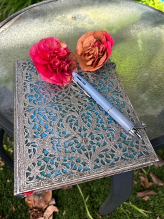 A decorative notebook and pen beside autumn flowers